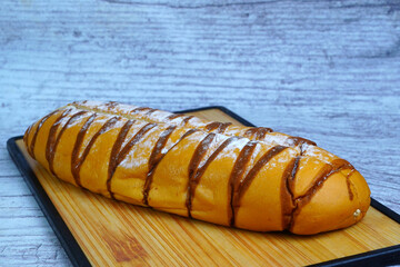 A golden-brown mocha loaf with chocolate drizzle and powdered sugar, resting on a wooden cutting board.
