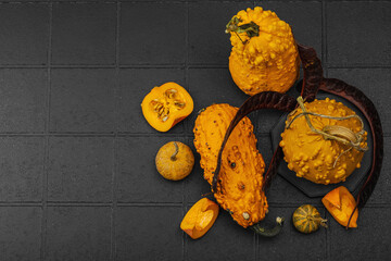 Organic ornamental pumpkins with textured skin and cut slices on dark background. Natural concept