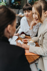 Three businesswomen collaborate and discuss ideas in a professional yet casual environment.