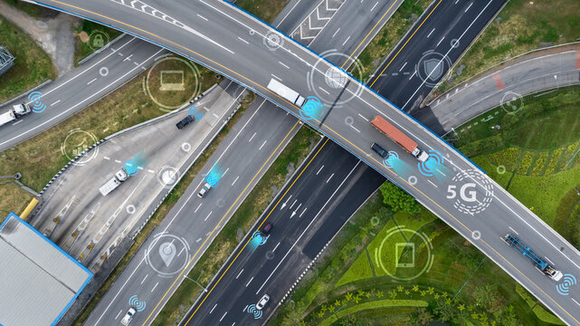 Aerial view of modern highway interchange with autonomous vehicles and connectivity symbols. Smart traffic systems and 5G technology for future transportation and intelligent mobility solutions.