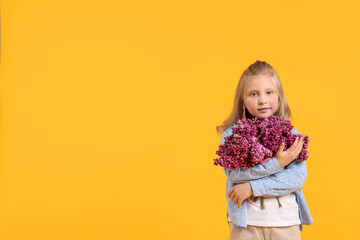 Little girl with bouquet of lilac flowers on yellow background, space for text