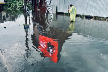 Unrecognizable man trying to unclog the draining system after a heavy rain fall due to climate change in Bucharest, June 2025.
