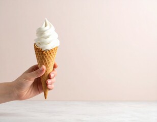 Lody w rożku trzymane w ręku na tle muru