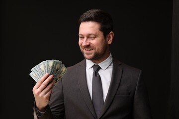 Happy greedy banker with dollar banknotes on black background