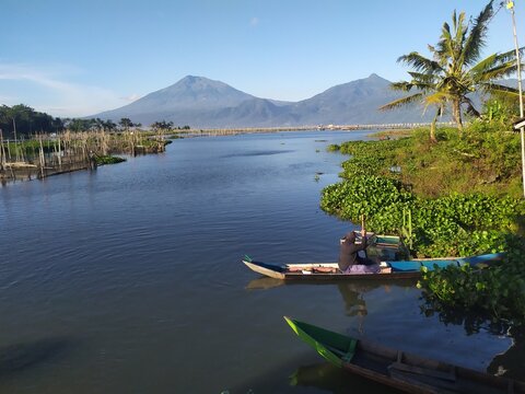 two fishermen on the rowing boat with mountains and blue sky in the background