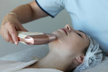 closeup portrait  of young woman receives a HIFU (High-Intensity Focused Ultrasound) facial treatment at a modern aesthetic clinic. 