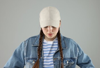 Woman in stylish baseball hat on grey background