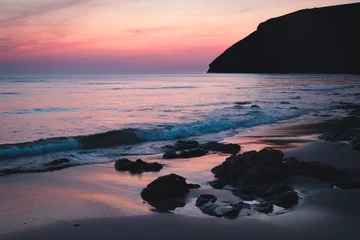 Fototapete Lavendel Tranquil twilight on serene beach, soft pink and purple hues reflecting calm ocean waters with reflections, silhouettes of rocks, peaceful beauty coastal landscape dusk, Mawgan Porth, Cornwall, UK  © Carla Tracy