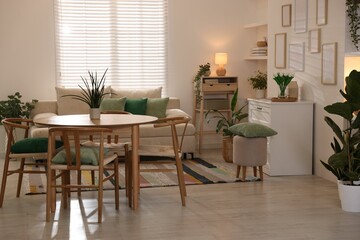 Stylish dining table with chairs and comfortable sofa in room. Interior design