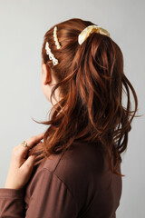 Woman with beautiful hair accessories on light grey background
