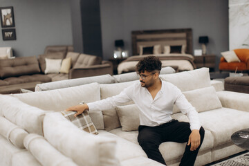 Man Choosing Sofa in Modern Furniture Store with Stylish Interior Design