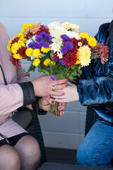 Hands exchanging a vibrant bouquet of mixed flowers in a cozy setting on a sunny day, capturing an emotional moment of gratitude and connection between two people