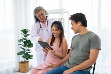 Senior female obstetrician consulting pregnant woman and her husband in medical clinic or hospital planning pregnancy. Visit to hospital, planning pregnancy, happy patients, trust and respect concept