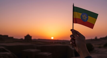 Patriotic sunset: Holding the Ethiopian flag against a vibrant horizon glow