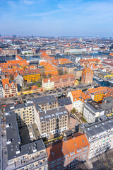 This aerial view captures the vibrant rooftops of residential buildings in Copenhagen, Denmark. Colorful facades contrast with the blue waters and sky, showcasing the city's charm and culture.