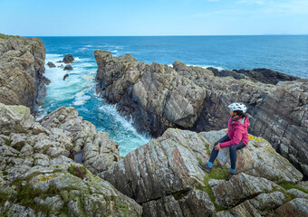 nice senior woman resting during a bicycle tour in the rocky cliffs of Strathy Point in northern...