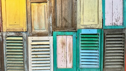 A vibrant collection of vintage wooden windows, each painted in bright, weathered colors that reflect the rich cultural charm of Indonesia. Colorful wooden windows background