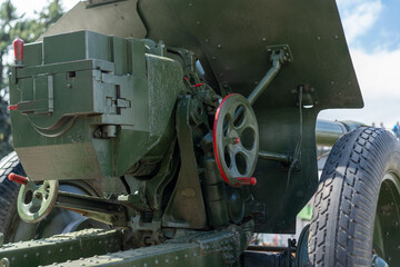 Historical artillery piece on display at military event during sunny afternoon