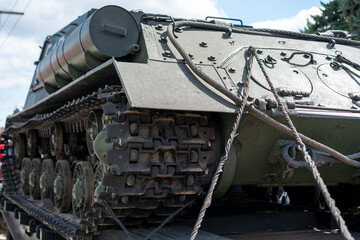 Military tank being transported on a flatbed trailer during the daytime in an outdoor setting