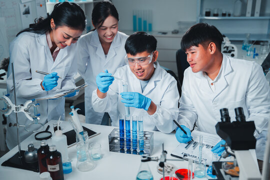 A diverse team of young scientists conducts a chemistry experiment, carefully analyzing blue liquids in test tubes, demonstrating teamwork, focus, and precision in a modern laboratory setting.