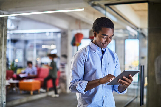 Confident young man working on a digital tablet in a modern office setting