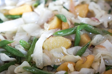 Close up view of stir fry vegetables in a pan. Cabbage, long beans and potato.