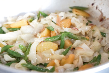 Close up view of stir fry vegetables in a pan. Cabbage, long beans and potato.