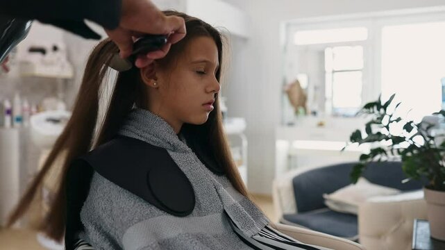 Professional hairdresser skillfully drying long brown hair of beautiful girl while providing expert hair care service in a vibrant beauty salon.