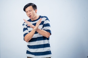 Asian man in striped shirt makes an X gesture with both arms and an angry expression, clearly...