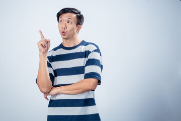 Asian man in navy and white striped t-shirt raising one index finger with an enthusiastic smile,...