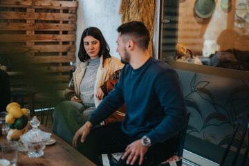 Two individuals sit at a table in a cozy and inviting indoor cafe. The atmosphere is warm, with...