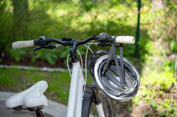 Close-up of handlebar and seat of bicycle, helmet hangs on handlebar. Safe and eco-friendly way of transportation