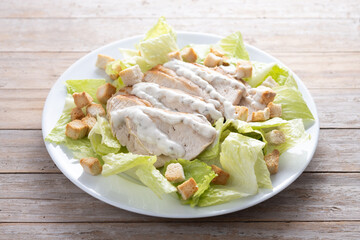 Crunchy Caesar salad with chicken on wooden table