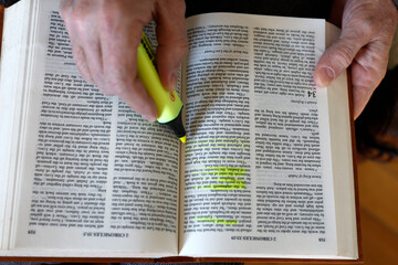 Naklejka premium Man studying the Bible and highlighting important passages. Bible study.