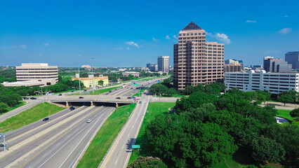 Fototapeta premium Lush green Las Colinas downtown with new commercial property under construction, glass office building, high-rise towers, multilevel parking garage, golf course along John Carpenter Freeway 121