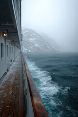 Snowy cruise: An amazing view of majestic mountains from a ship sailing through the rough, cold seas.
