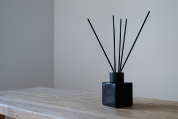 Modern composition of perfume in black glass diffuser with sticks on mimimal background for home aromatherapy.
