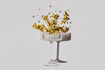 Champagne glass, serpentine and golden stars on white background. Shiny greeting card for Christmas, wedding or birthday party.