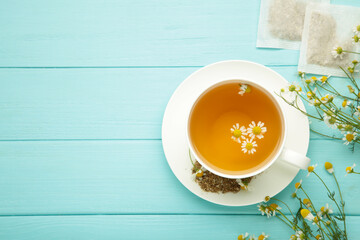 Chamomile tea bag, herbal chamomile tea with fresh daisy flowers on blue wooden background. Immune...
