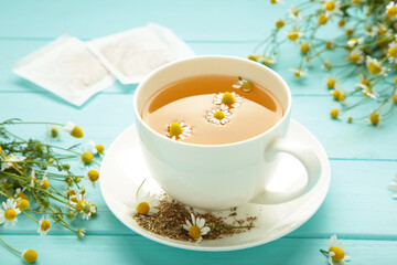 Chamomile tea bag, herbal chamomile tea with fresh daisy flowers on blue wooden background. Immune concept