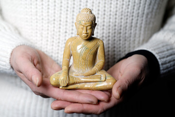 Woman with ˆ marble seated  Buddha in hands.