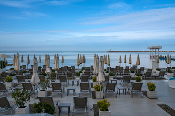 A deserted beach on the coast of Sochi with sun beds and umbrellas against the background of the calm Black Sea, Adler, Krasnodar Territory, Russia