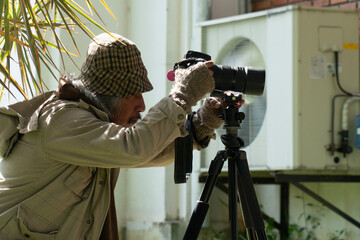 A photographer in warm attire captures an image, focusing intently while using a tripod in an...