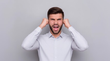 Businessman covers his ears and screams in anger against a grey background in a studio setting.