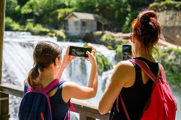 Family visiting famous Strbacki buk waterfall in national park Una River in Bosnia and Herzegovina. Tourists taking photos of the amazing waterfall Strbacki Buk and river Una in Bosnia.