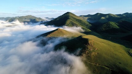 Aerial view of mist-shrouded hills and grasslands, with high mountains towering among green peaks and surrounded by white mist, symbolizing tranquility and beauty.