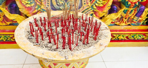 Red bamboo sticks left over from burning incense are placed in pots inside temples or shrines. Stick of incense was fully lit or red stick left from extinguished incense in brightly colored cement pot