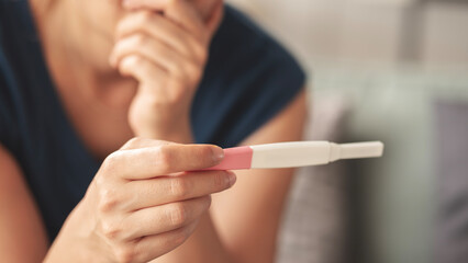 Young woman holding pregnancy test with negative result