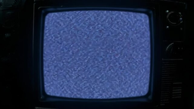 Close-up of an old CRT television showing glitch patterns and static noise. Colored lines flicker and distort, creating a nostalgic VHS-style interference effect perfect for retro, tech, or cinematic 