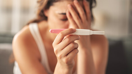 Young woman holding pregnancy test with negative result
